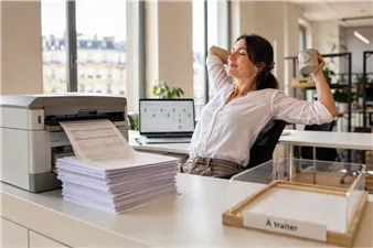 Relaxed employee at her desk, the “to process” mail pile already printed